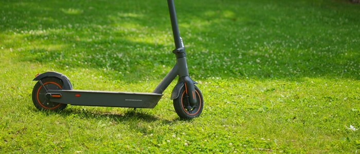 E-Roller steht auf einer Grasfläche in einem Park