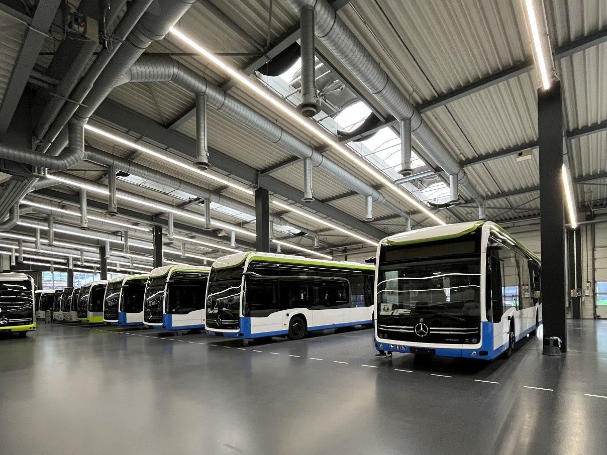 5 Busse stehen abholbereit in einer Fahrzeughalle.